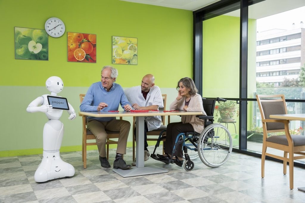 Digitalizált egészségügy: Pepper robot páciensekkel és egy ápolóval egy német kórházban
