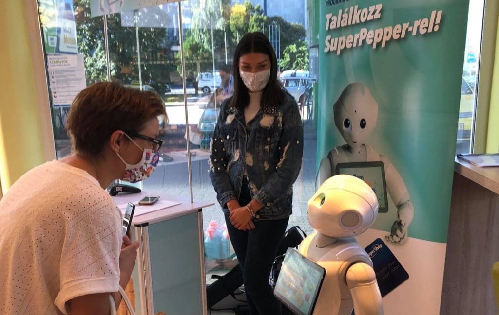 Pepper robot is talking with a lady at a petrol station, Budapest